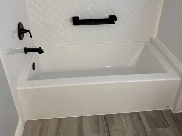 Jacuzzi® bathtub with a white herringbone wall surround and matte black fixtures